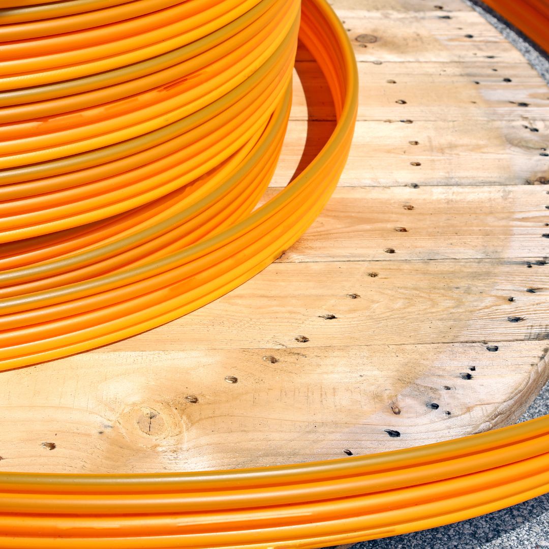Coil of orange fiber conduit on a wooden reel