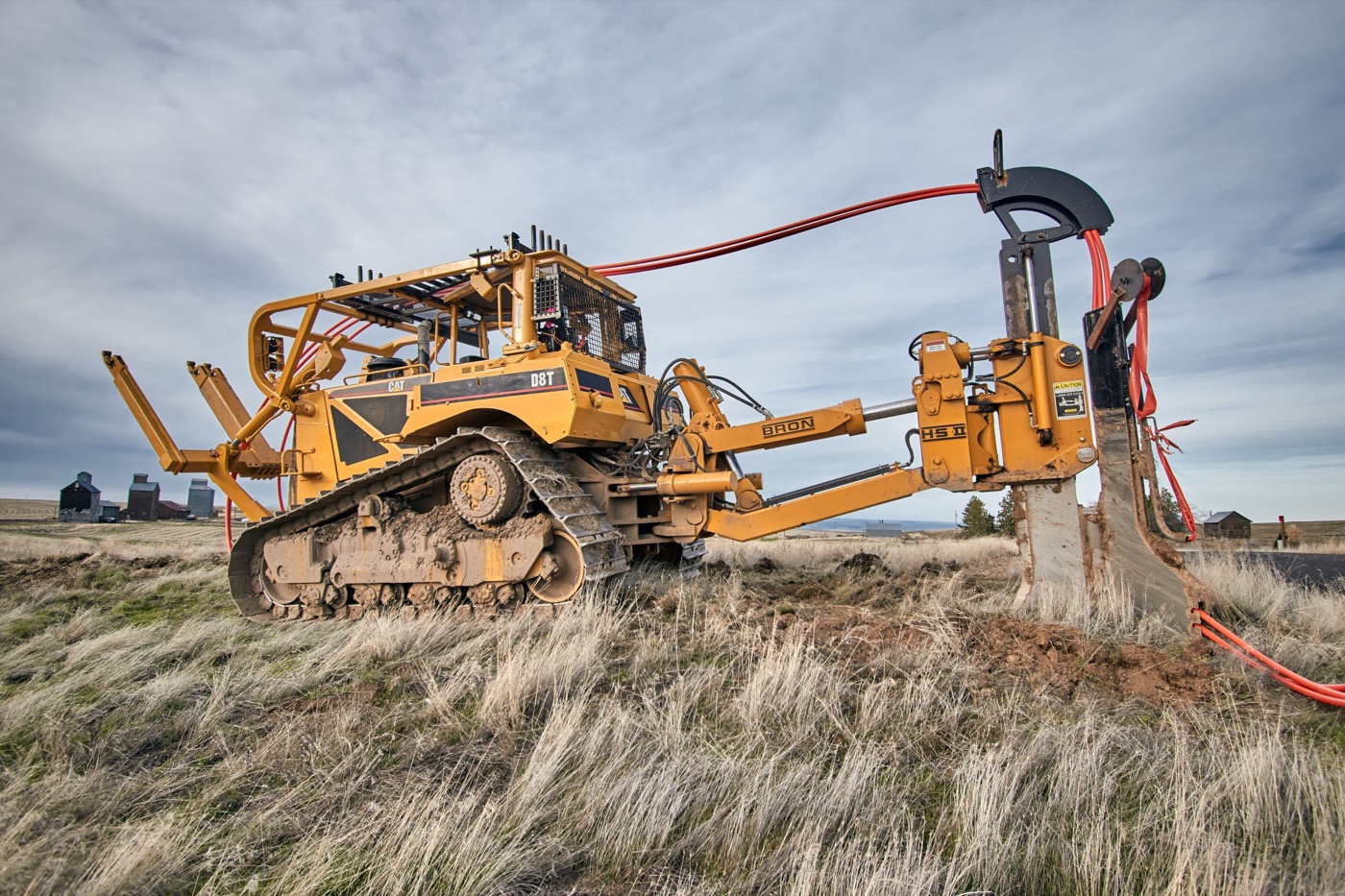 Tractor-drawn cable plough placing fiber across a field